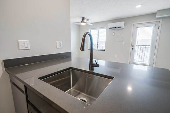 a drop-in kitchen sink with a gooseneck faucet in a stone countertop