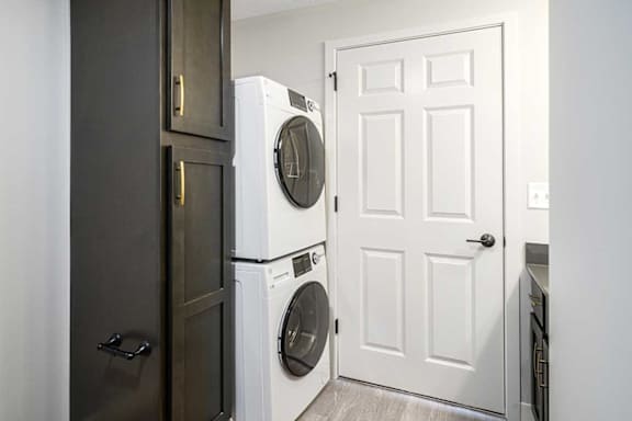 a stacked washer and dryer next to a tall storage cabinet