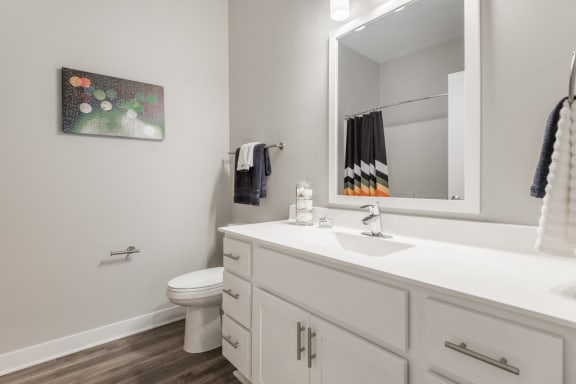 Bathroom with white cabinets and white, cultured-marble countertops