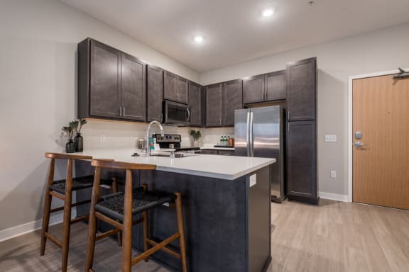 U-shaped kitchen with dark brown cabinets, stainless appliances, and white counters