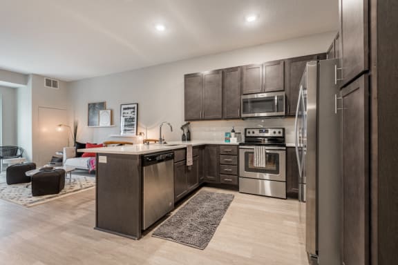 U-shaped kitchen with dark brown cabinets, stainless appliances, and white counters