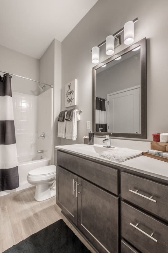 Bathroom with dark cabinets and white, cultured-marble countertops at The Preserve at Normandale Lake