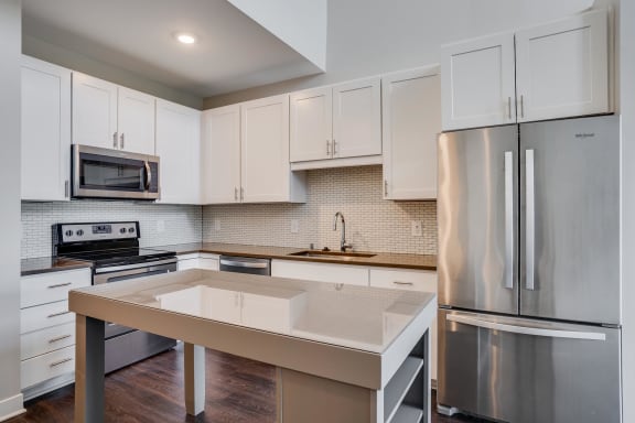 The Harriet features modern white cabinets, stainless appliances,  and a movable kitchen island