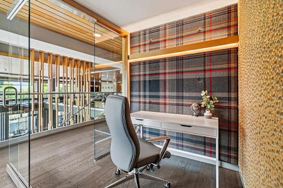 A work from home suite with a desk, leather swivel chair, and glass door wall.