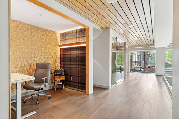 A view of private work-from-home suites with desks, office chairs, and textured accent walls in a modern clubhouse.
