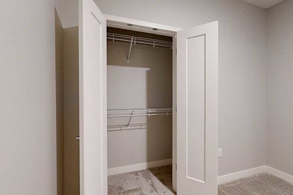 A den space with a double-door closet with built-in wire shelves.