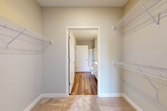 An oversized walk-through closet with several built-in wire shelves, connected to a bathroom.