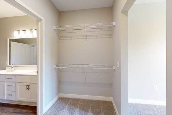 An oversized walk-through closet with several built-in wire shelves, connected to a bathroom.