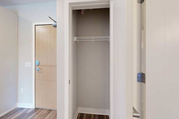 A coat closet with a built-in wire shelf.