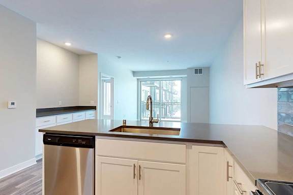 A large kitchen peninsula in front of a spacious living room.