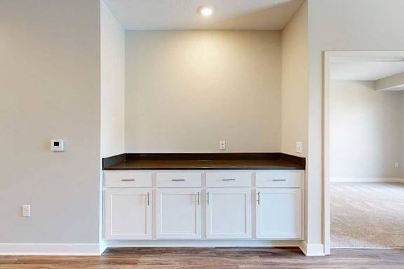 A row of built-in cabinets with a dark countertop in a recess, creating a dry bar or storage space in the living room.