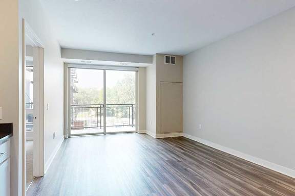 A living room with hardwood-style flooring and a sliding glass door to a balcony.