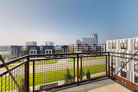 A balcony with a metal railing and a view of the neighborhood.