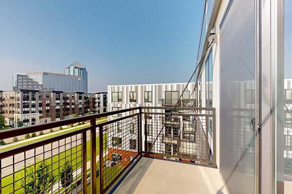 A balcony with a metal railing and a view of the neighborhood.