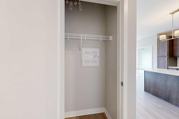 A coat closet with a built-in wire shelf.