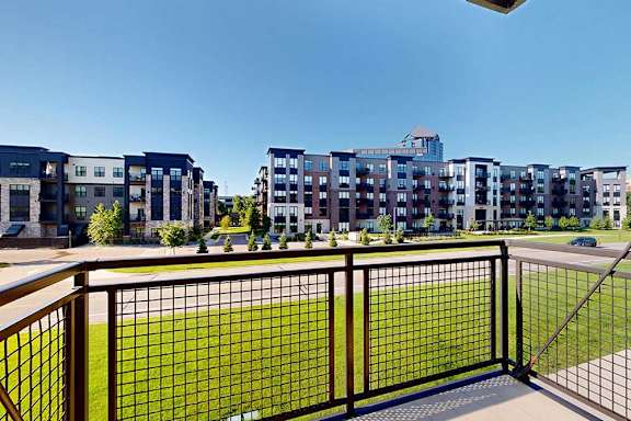 A balcony with a metal railing and a view of the neighborhood.