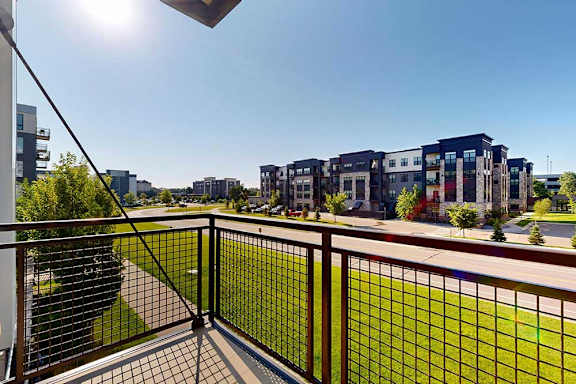 A balcony with a metal railing and a view of the neighborhood.