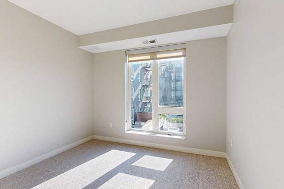A carpeted bedroom with a floor-to-ceiling window.