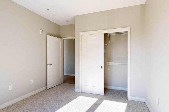 A carpeted bedroom with a sliding-door closet.