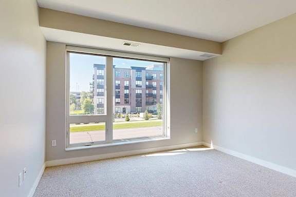 A carpeted bedroom with a floor-to-ceiling window.