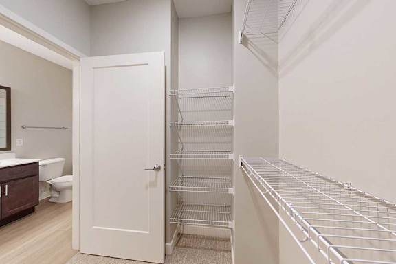 An oversized walk-in closet with several built-in wire shelves connected to the primary bathroom..