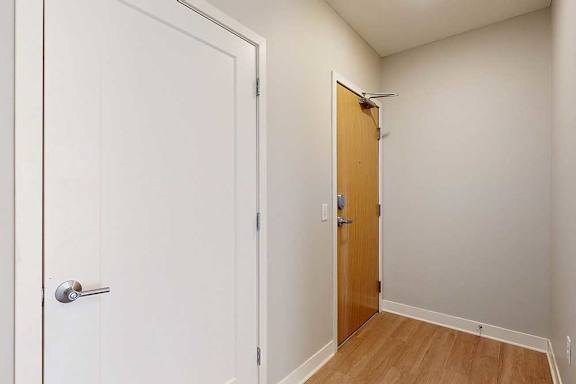A front entryway with a wooden front door and a coat closet.