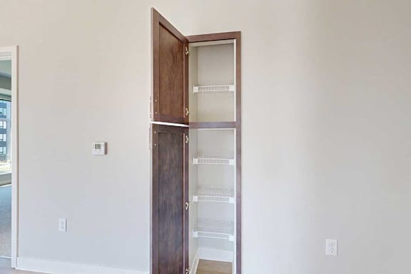 An open kitchen pantry with several built-in wire shelves.