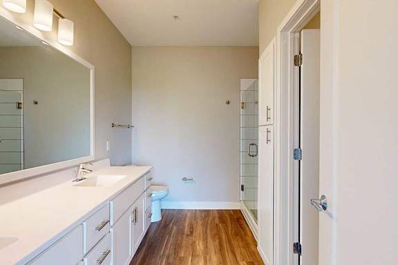 A bathroom with a white counter top and a wooden floor.