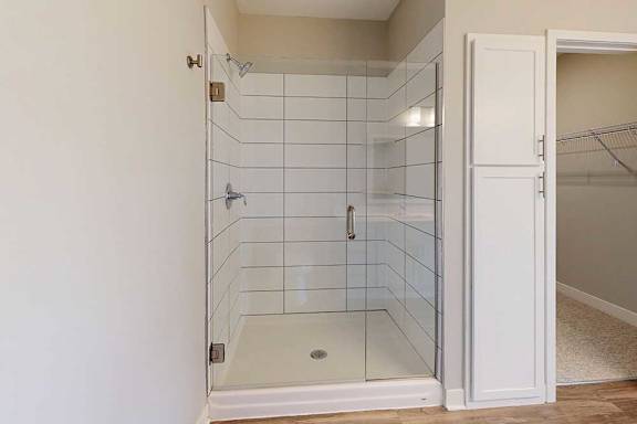 A bathroom with a tiled walk-in shower with a glass door.