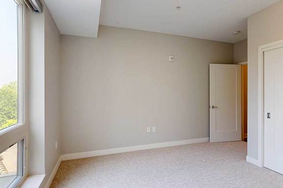 A carpeted bedroom with a floor-to-ceiling window and a sliding-door closet.