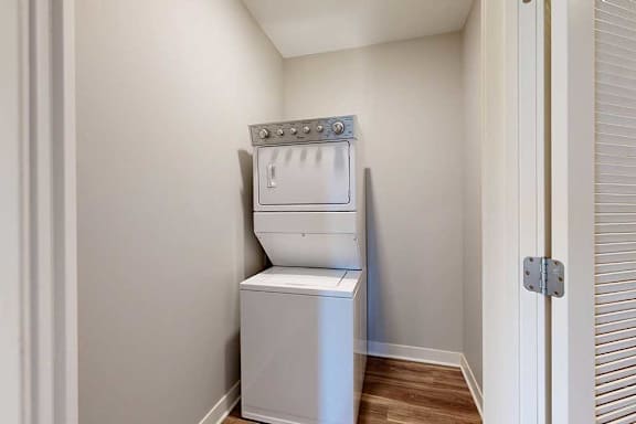 A stacked full-sized washer and dryer in a laundry closet.