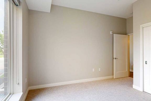 A carpeted bedroom with a floor-to-ceiling window and sliding-door closet.