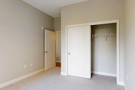 A carpeted bedroom with a sliding-door closet.