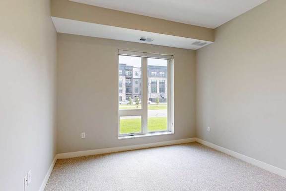 A carpeted bedroom with a floor-to-ceiling window.