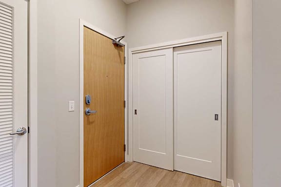 A front entryway with a wooden front door and a sliding door coat closet.