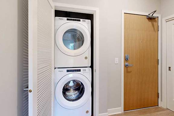 A stacked full-sized washer and dryer in a laundry closet.