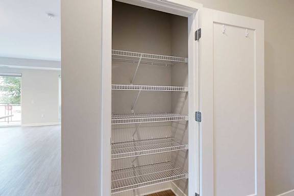 A hallway closet with several built-in wire shelves.