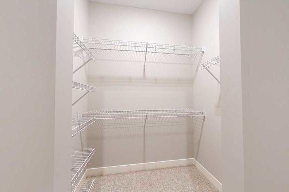 An oversized walk-in closet with several built-in wire shelves.