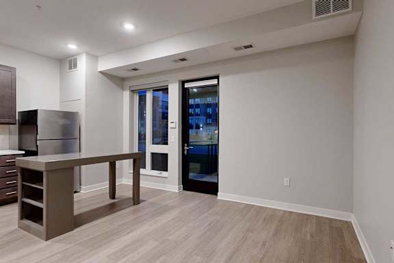 A living area with hardwood-style flooring and kitchen with dark wooden cabinets.