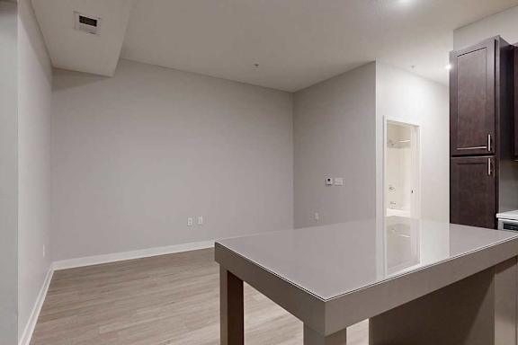 A kitchen island in front of a living area with hardwood-style flooring.