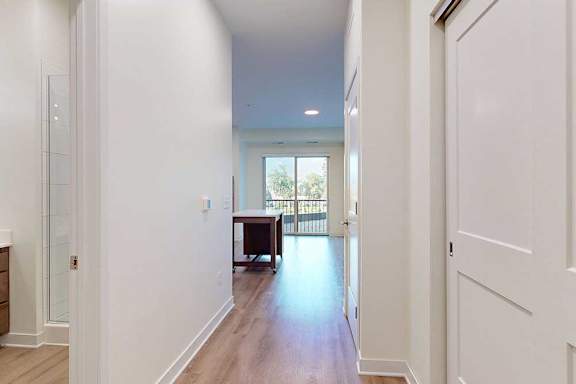 Apartment entryway with white walls and a bathroom to the left