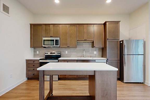 A kitchen with a moveable island and brown wood cabinets.
