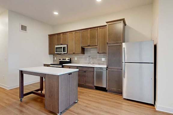 A kitchen with a white counter top and a stainless steel refrigerator.