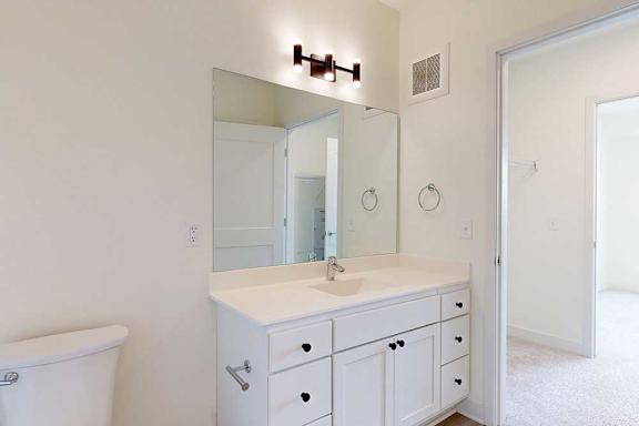 A white bathroom with a sink, mirror, and toilet