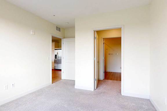 A room with a carpeted floor and two open doors.