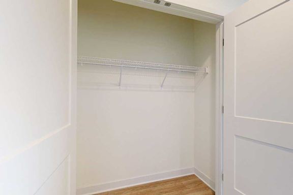 A white closet with a shelf and a door.