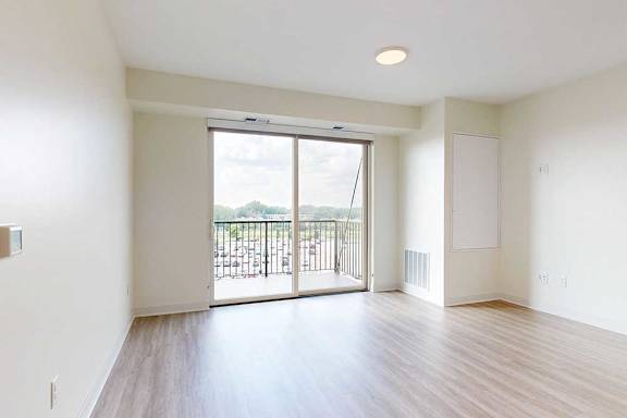 A spacious room with a sliding glass door leading to a balcony.