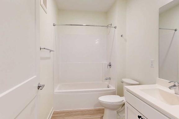 A white bathroom with a toilet, sink, and shower/tub combo