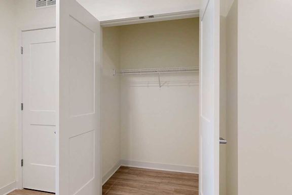 A white closet with a door and a shelf.