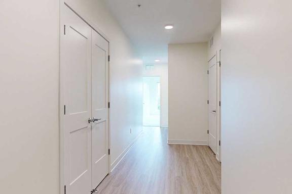 A long hallway with white doors and wood floors.